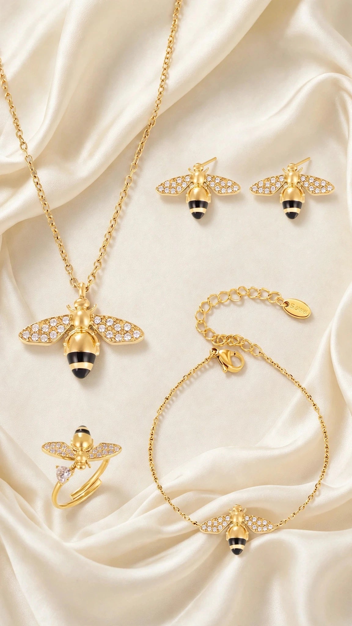 Abeja Dorada bee necklace, bracelet, earrings and ring arranged on ivory silk